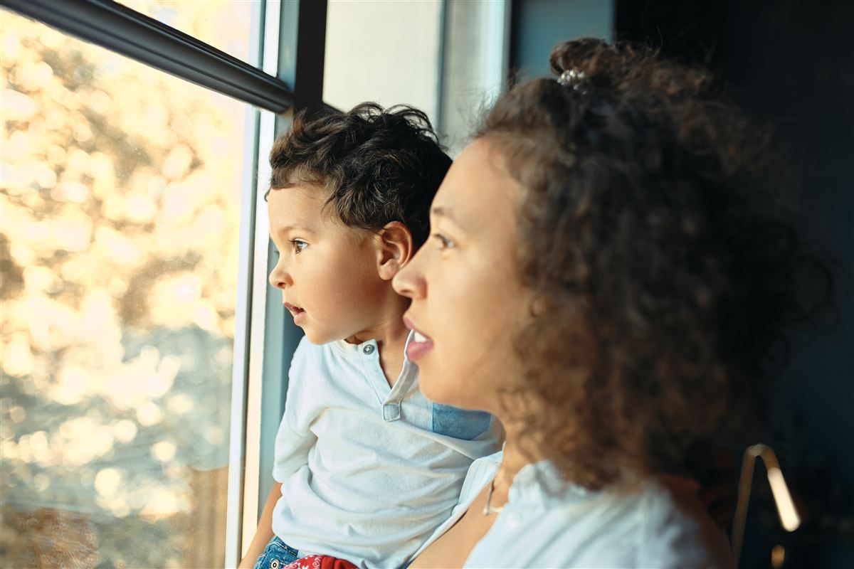 Mãe e filho pequeno olhando juntos pela janela, imagem da área de Direito de Família