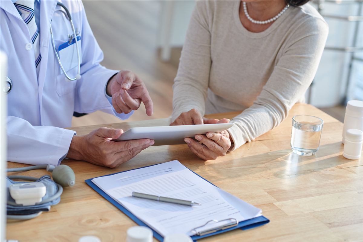 Médico mostrando informações em um tablet para uma paciente, imagem da área de Direito à Saúde